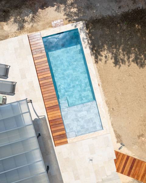 Piscine traditionnelle en PVC armé imitation pierre de Bali : design naturel et grande plage - Mcr Piscines et Spas, Gard