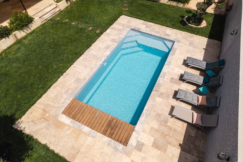     Installation piscine coque MOTU à Garons, gris quartz avec volet immergé et margelles en travertin gris. - MCR Piscines et Spas - Gard