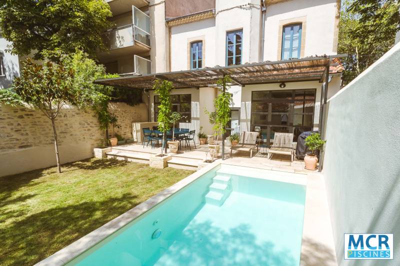 Piscine traditionnelle élégante avec membrane armée sable et margelles travertin beige - Mcr Piscines et Spas, Gard