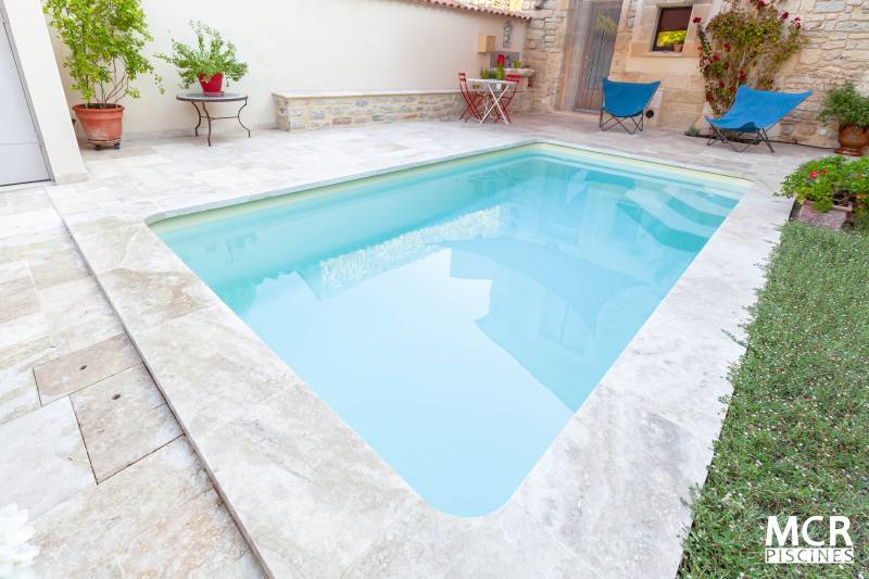 Pose d'une piscine coque polyester modèle MAJORQUE à Nages et Solorgues à côté de Calvisson dans le Gard avec margelles en travertin.