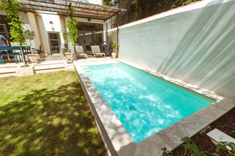 Piscine traditionnelle avec revêtement en membrane armée de couleur sable et margelles en travertins beige