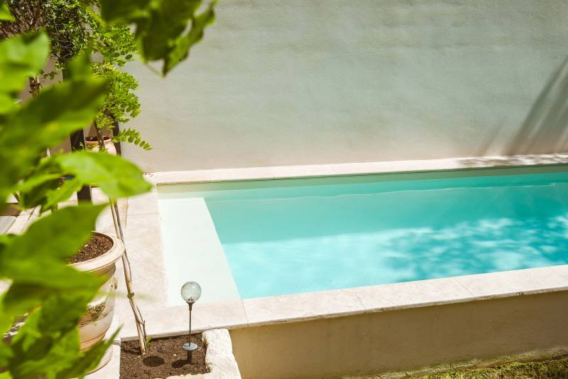 Piscine traditionnelle avec revêtement en membrane armée de couleur sable et margelles en travertins beige