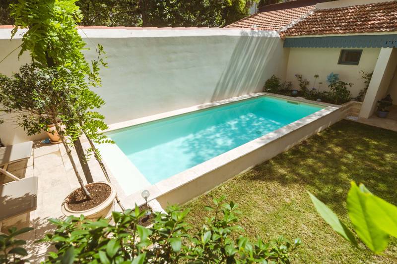 Piscine traditionnelle avec revêtement en membrane armée sable et margelles en travertin beige pour un jardin chic - Mcr Piscines et Spas, Vergèze